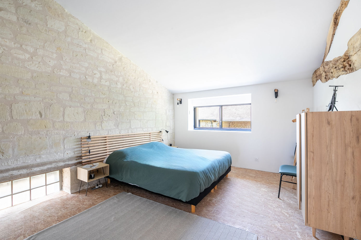 Chambre avec mur en pierre apparente et lit double
