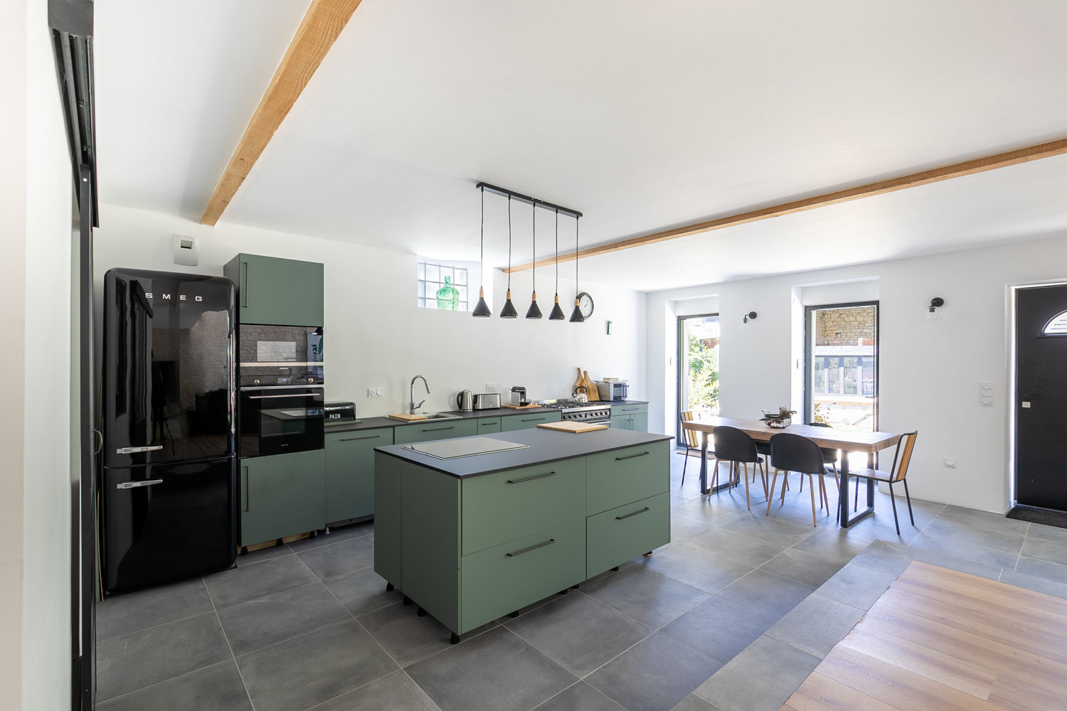 Cuisine équipée SMEG avec îlot central vert et coin repas