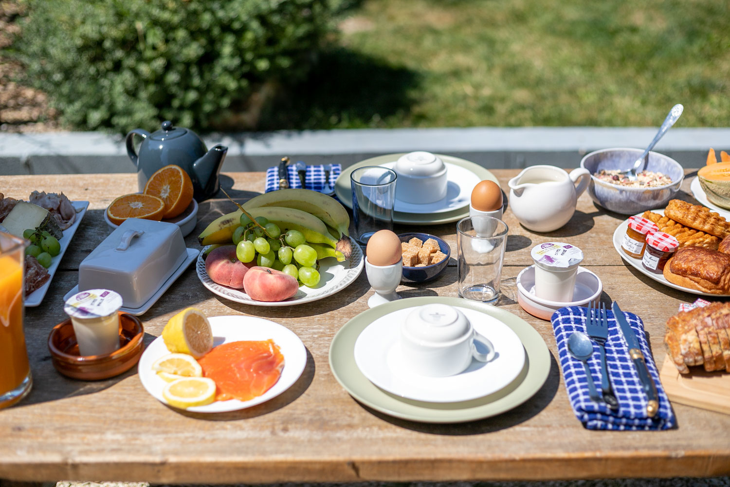 Petit-déjeuner dressé sur la table en bois de la terrasse
