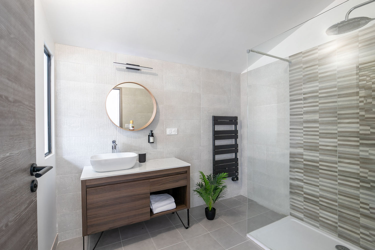 Salle de bain avec vasque sur meuble bois, miroir rond et douche à l'italienne