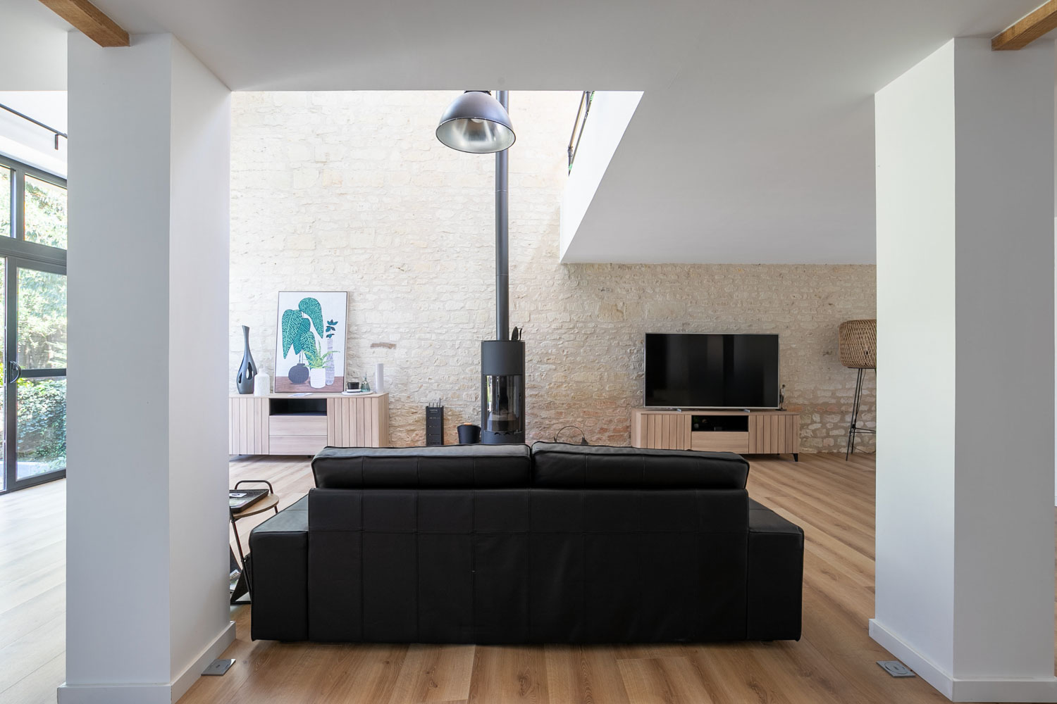 Coin salon avec canapé, poêle à bois et accès direct au jardin