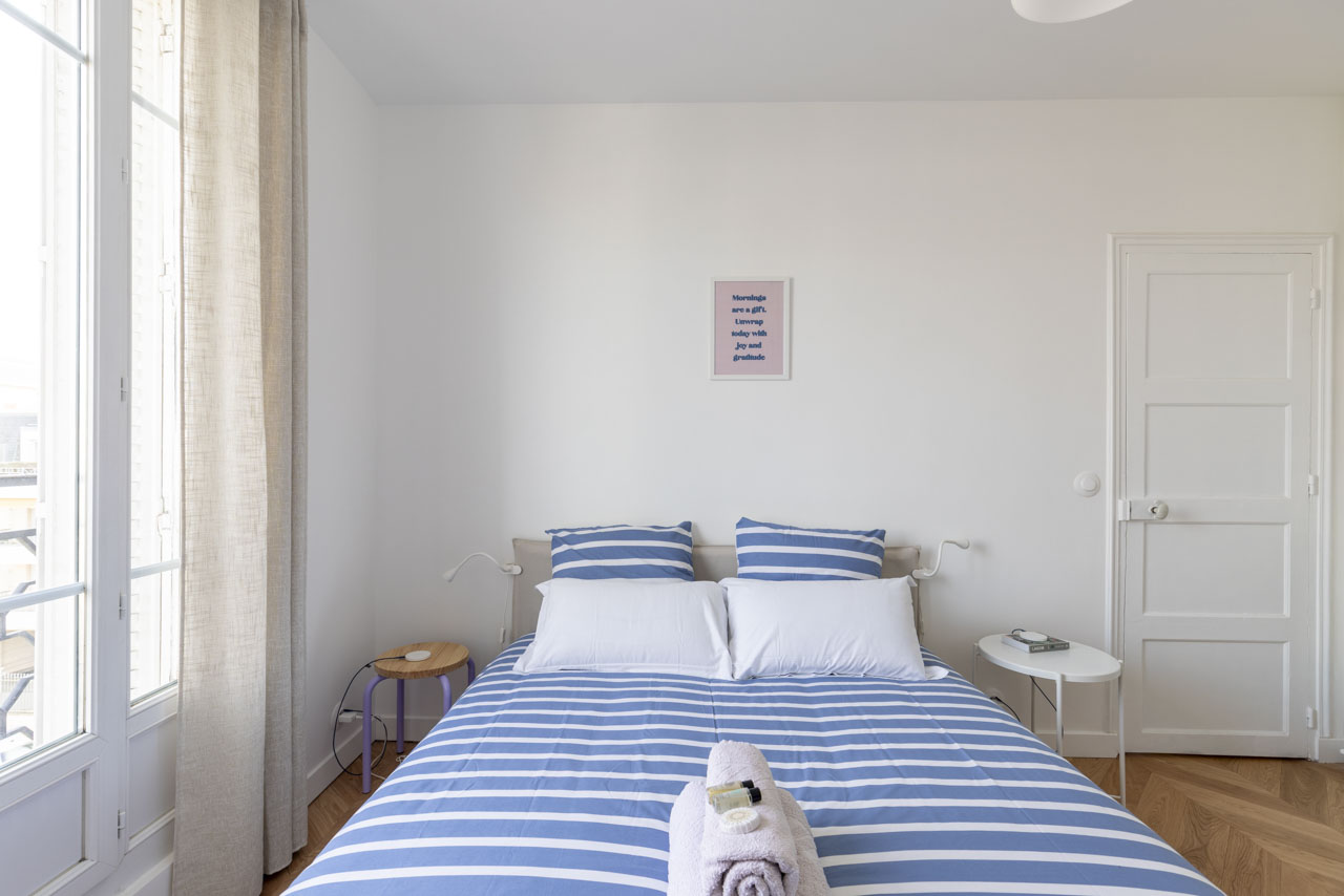 Chambre avec lit Queen 160 × 200 et fenêtre donnant sur la rue